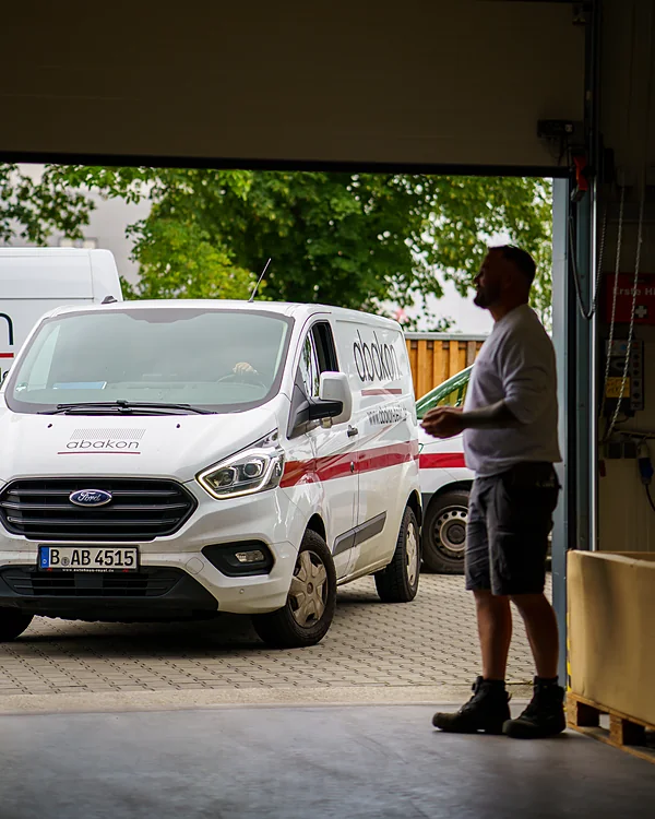 Blick aus der Halle: Ein Mitarbeiter steht im Tor, draußen fährt ein abakon-Transporter vor.