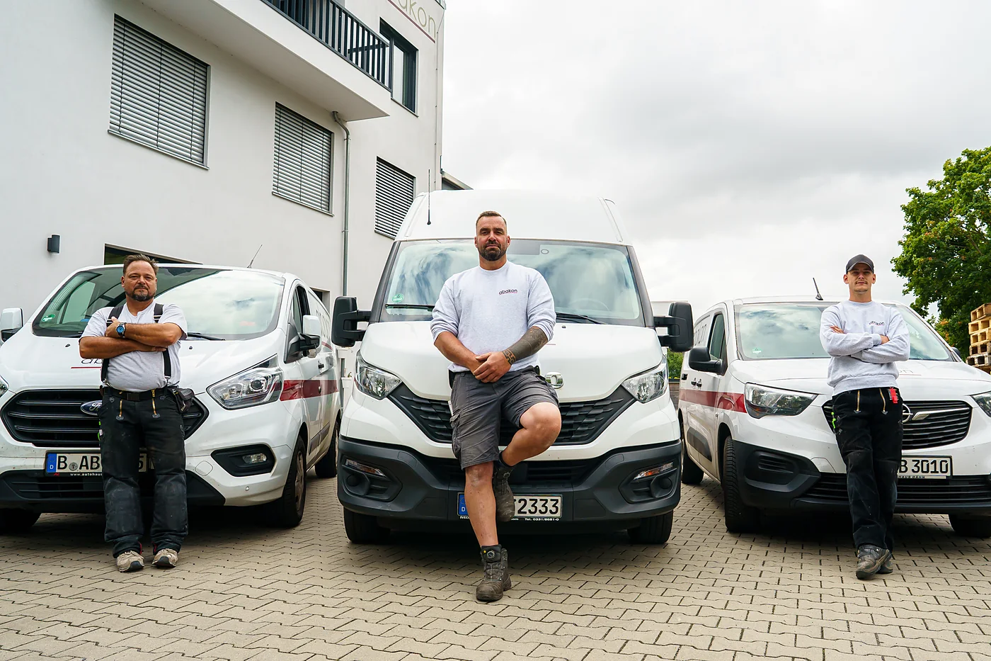 Drei Mitarbeiter vor einem abakon-Transporter mit dem Aufkleber Wir bilden aus.